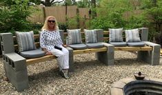 a woman is sitting on a bench made out of concrete blocks and cushions in the garden