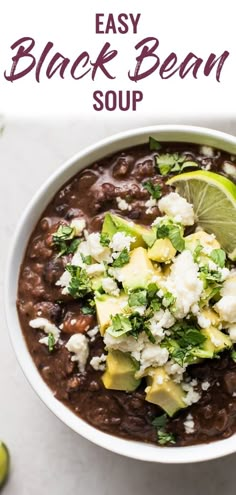 a white bowl filled with black bean soup topped with avocado and cilantro