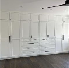 an empty room with white cabinets and wood floors