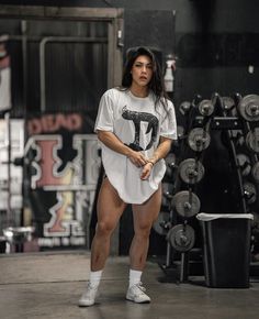 a woman standing in front of a rack of dumbs