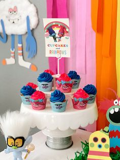 cupcakes with blue frosting and red icing are on a cake stand