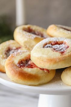 small pastries on a white plate with powdered sugar and jelly in the middle