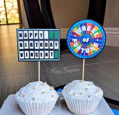 two cupcakes with white frosting are sitting on top of a board game