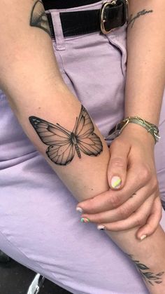 a woman's arm with a butterfly tattoo on the left wrist and right hand