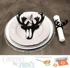 a white plate topped with black antlers next to a pair of scissors and napkins