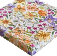 a white box with colorful flowers on it's sides and an orange, yellow, purple, and pink flowered design