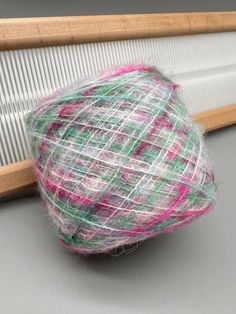 a ball of yarn sitting on top of a table next to a wooden frame and weaving machine