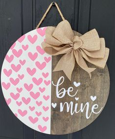 a wooden sign that says be mine with hearts and a bow hanging from the front door