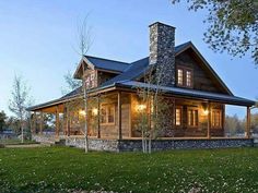 a rustic log cabin with stone and wood accents at dusk, lit by lights on the front porch