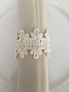 the napkin is crocheted with white thread and sits on a plate next to a fork