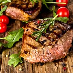 two steaks with fresh herbs and tomatoes on the side, ready to be eaten