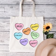 a tote bag with candy hearts on it next to a hat and sunflower