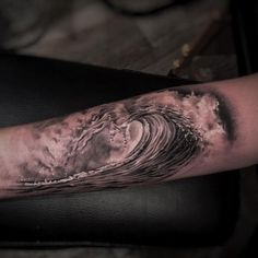 a man's arm with an ocean wave tattoo on the inside of his arm