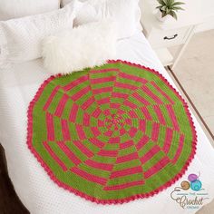 a crocheted round rug on top of a bed in a room with white walls