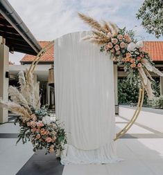 an arch decorated with flowers and pamodia stands in front of a white building