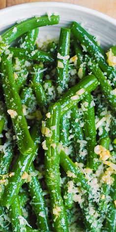 a white bowl filled with green beans covered in parmesan sprinkles