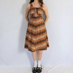 "Vintage sleeveless midi dress Classic 1960s a-line dress! Has a corseted bust and an empire waistline, that ties into a bow at the back. Multi coloured knit in shades of brown, orange and beige. This dress isn't lined, and the interior feels a bit rough/stiff. Has a back zipper closure. Made in the 1960s in England, brand unknown. Great condition, the fabric has stiffened a bit and the brand tag has faded Full measurements are provided Measurements taken flat Tag size: 9 (medium) Chest: 32\" (can be tightened to 28\") Waist: 28\" Hip: 42\" Length: 41\" Fabric content: Polyester, acrylic, nylon" Sleeveless Brown Tiger Print Dress, 1970’s Mini Dress, 1970s Sleeveless Vintage Spring Dress, 1970s Sleeveless Cotton Dress, 1970s Sleeveless Floral Print Dress, Skirt Y2k, Peter Pan Collar Dress, Empire Waistline, Sleeveless Midi Dress