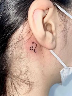 a woman's behind the ear has a small zodiac sign tattoo on her left side