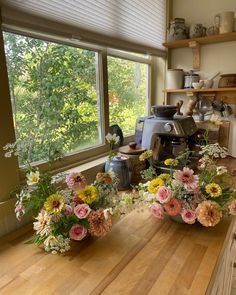 two vases filled with flowers sitting on top of a wooden counter next to a window