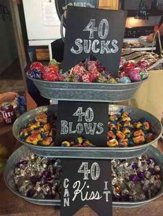 a three tiered tray filled with lots of candies next to a sign that says 40 sucks