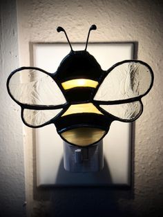 a close up of a light on a wall with a bee shaped object in the middle