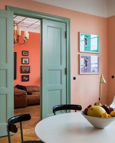 a bowl of fruit sitting on top of a white table in front of a door