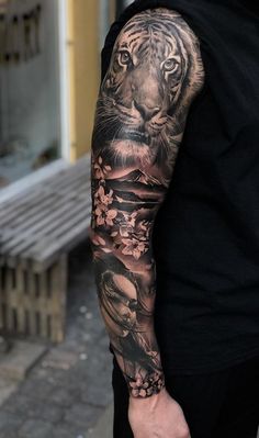 a man's arm with a tiger and flowers tattoo on the left side of his arm