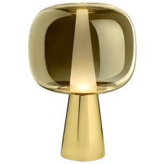 a gold colored table lamp on a white background with the light reflecting off it's side