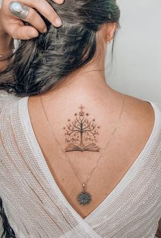 a woman with a tree tattoo on her upper back neck and book in the middle