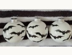 three ornaments with bats painted on them are sitting on a black and white striped blanket