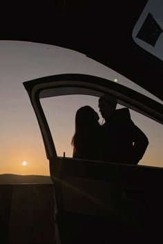 a man and woman are sitting in the back of a car as the sun sets