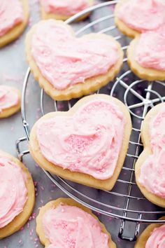 heart shaped cookies with pink frosting on a cooling rack