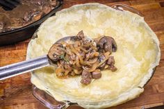 mushrooms being cooked in a skillet on a wooden table