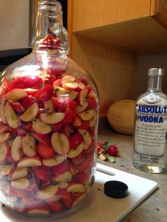 a glass bottle filled with sliced apples on top of a counter