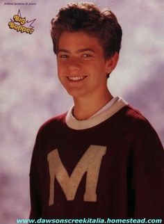 a young man in a maroon sweater smiling