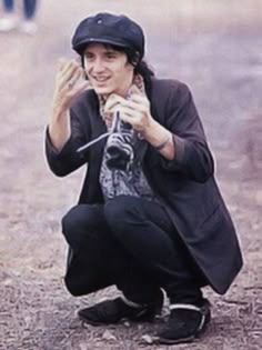 a man kneeling down while holding something up to his face and smiling at the camera