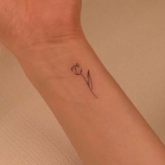 a small wrist tattoo with a single tulip on the left side of the arm