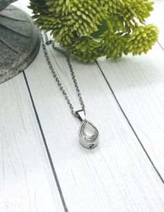 a close up of a necklace on a table with flowers and a vase in the background