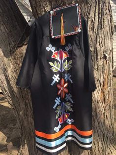 an embroidered dress hanging on a tree in front of a house with a tasseled neckline