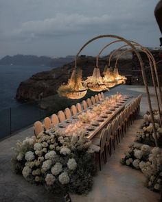 an outdoor dining area with tables and chairs set up for a formal dinner overlooking the ocean