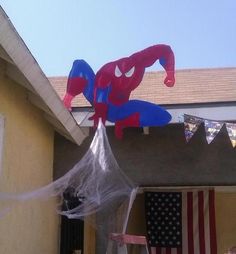 a spider - man kite is hanging from the roof of a house