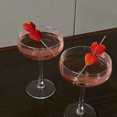 two wine glasses with strawberries in them on a table