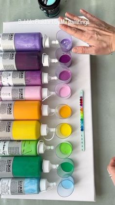 someone is holding their hand over some paint bottles