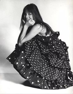 a black and white photo of a woman in a polka dot dress sitting on the floor