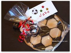 a soccer ball wrapped in plastic with a name tag and ribbon tied around the top