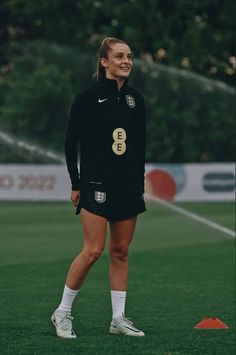 a female soccer player smiles as she stands on the field