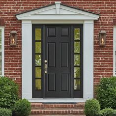 a black front door with two sidelights on the brick wall and windows above it