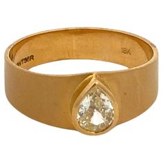 a yellow gold ring with a pear shaped diamond