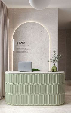 a green circular counter with a laptop on it in front of a white wall and window