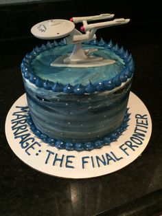 a star trek cake is decorated with blue frosting and starship on it's top